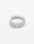 Load image into Gallery viewer, A silver huggie hoop ring featuring a row of clear round-cut cubic zirconia stones along the front band,