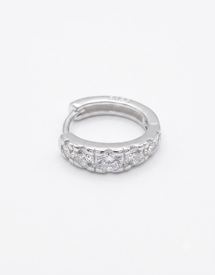A silver huggie hoop ring featuring a row of clear round-cut  cubic zirconia stones along the front band,
